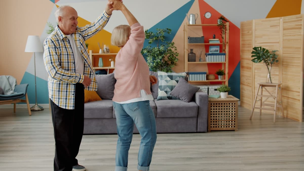 Pareja mayor bailando alegre en el living de su casa