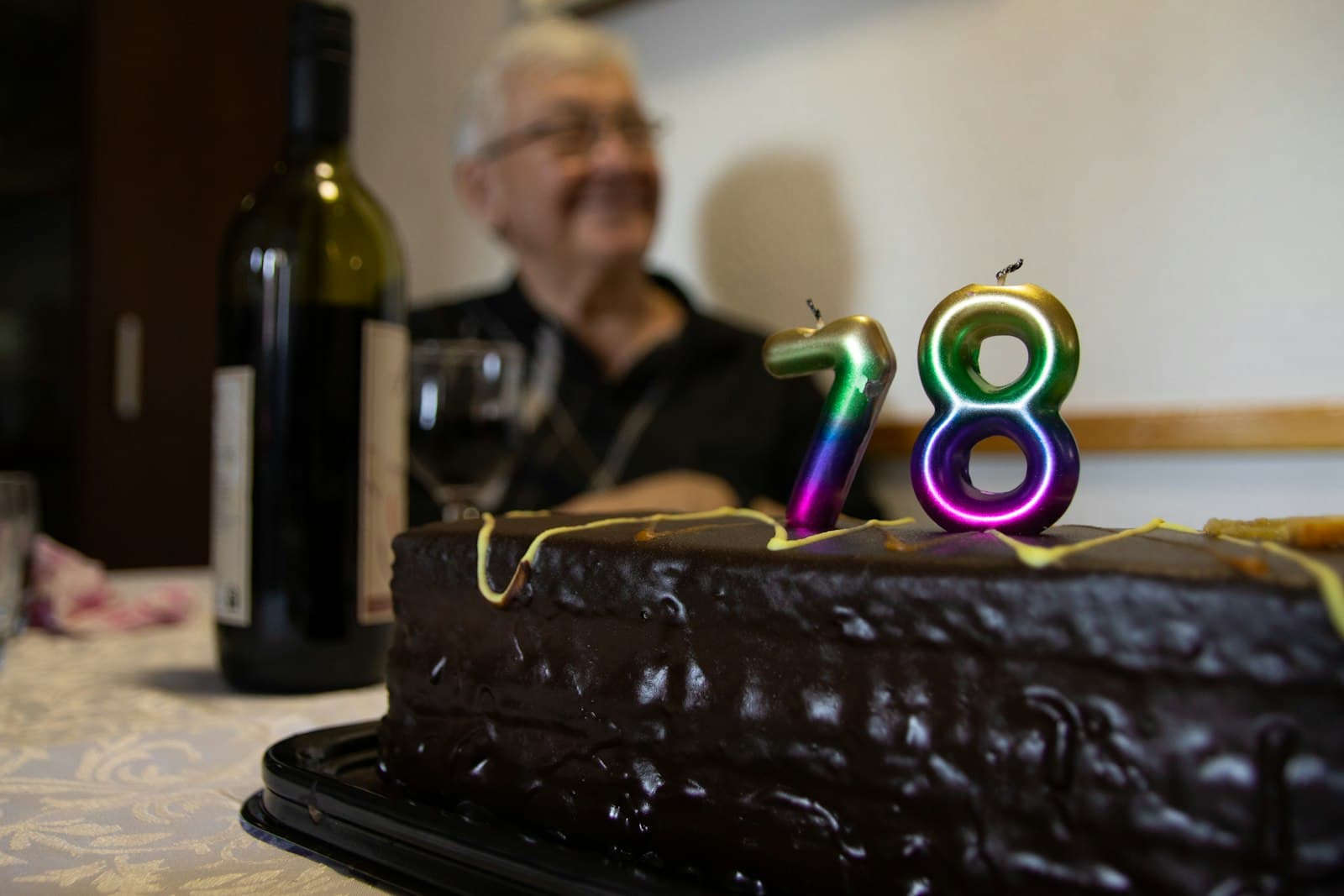 Hombre sentado frente a una torta con el número ochenta