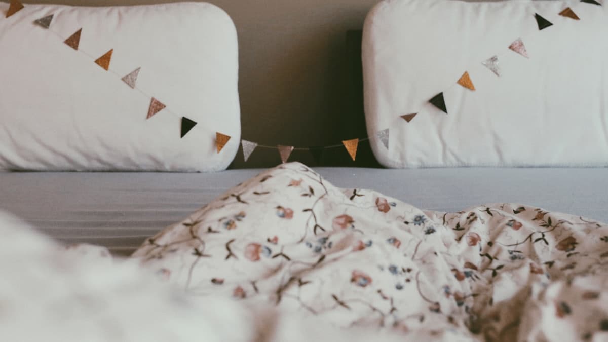 Cama con almohadones y una guirnalda de banderines colgada