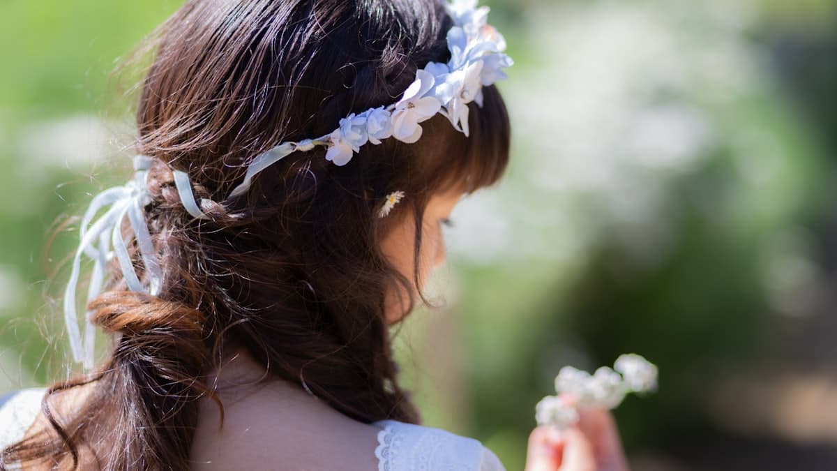 Nena con corona de flores sosteniendo pequeñas flores blancas