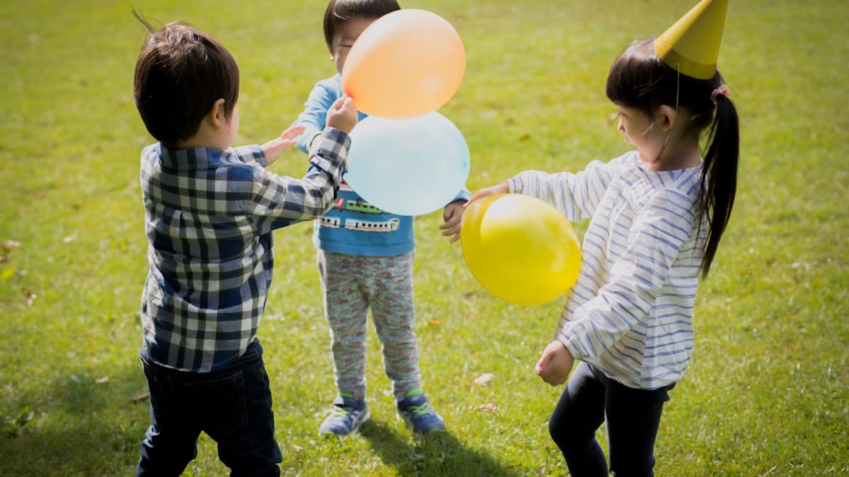 Chico sosteniendo globos amarillos en una fiesta de cumpleaños