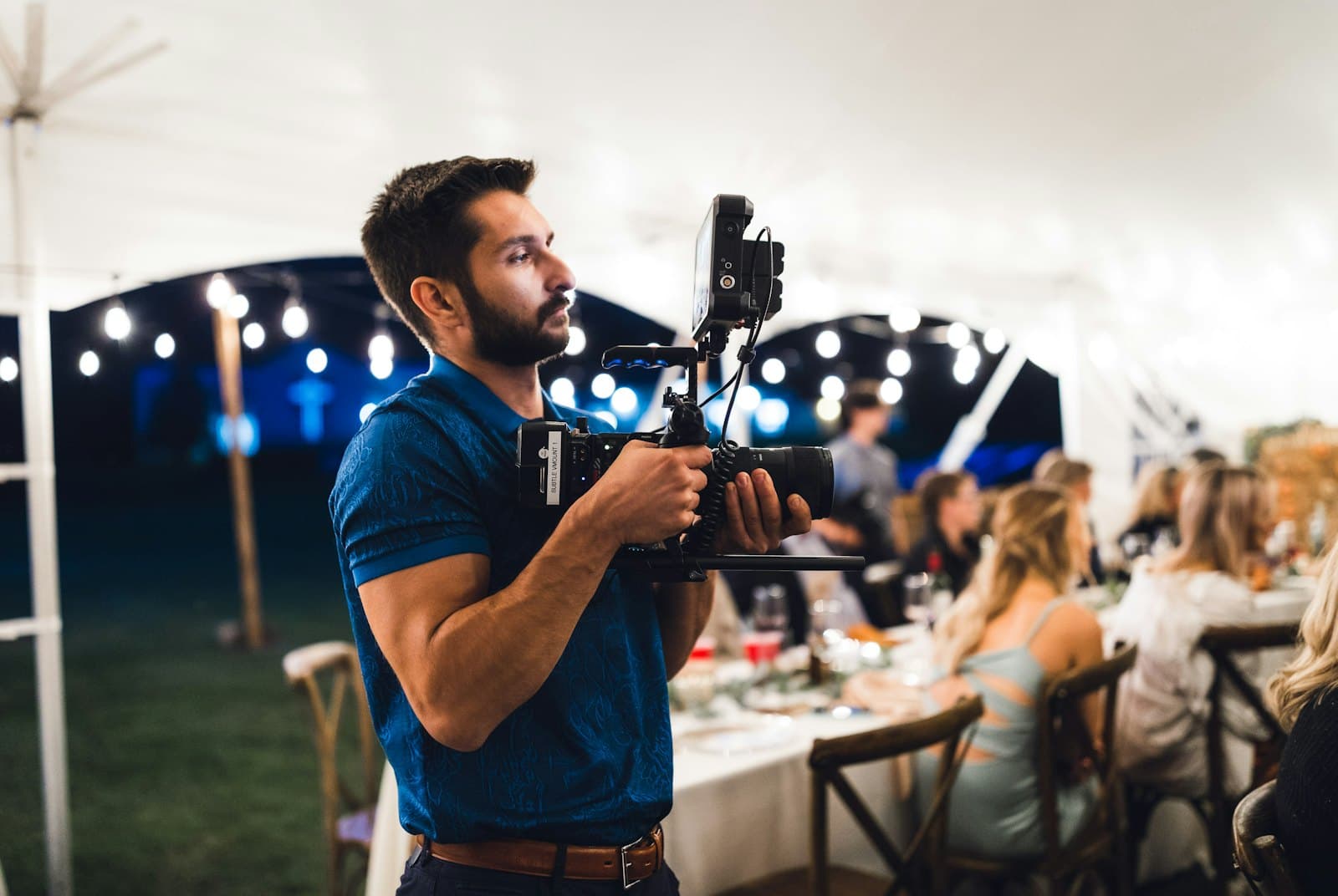 Fotógrafo con su cámara en un casamiento, con los invitados en las mesas detrás