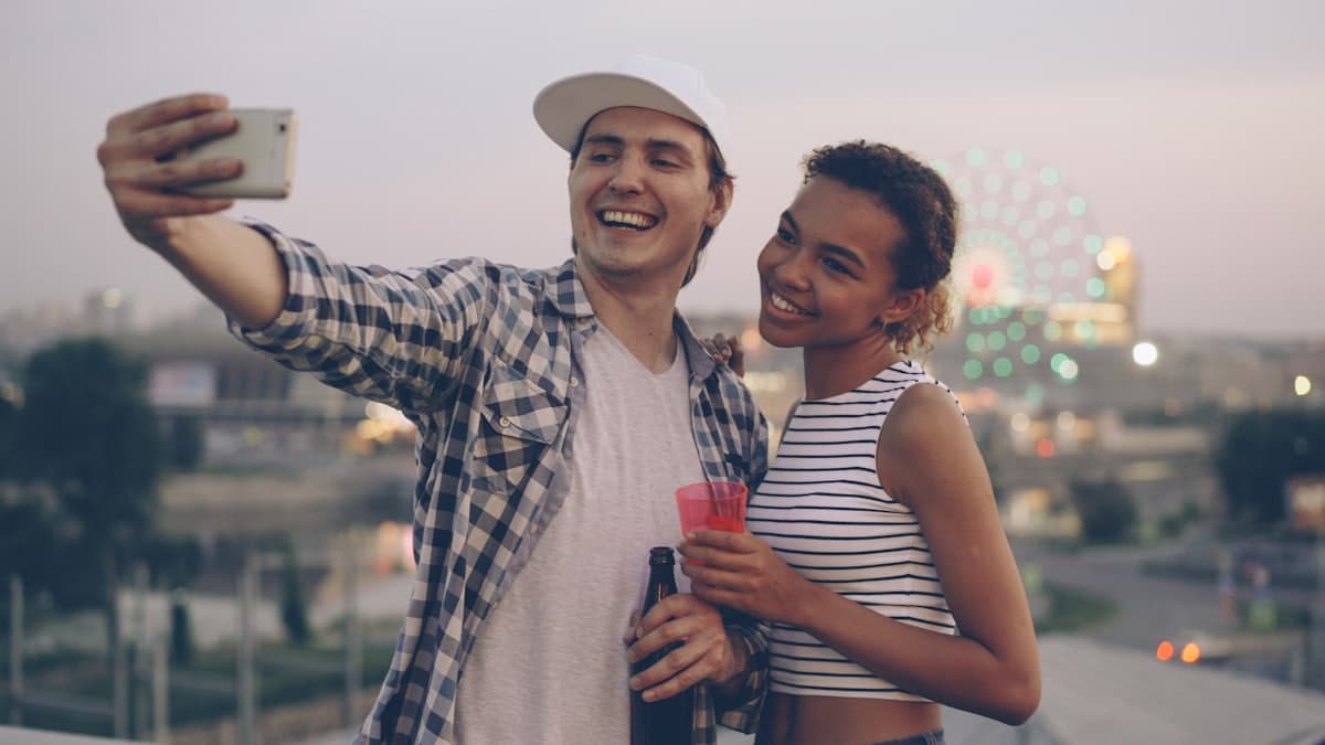 Pareja sacándose una selfie con las luces de la ciudad de fondo
