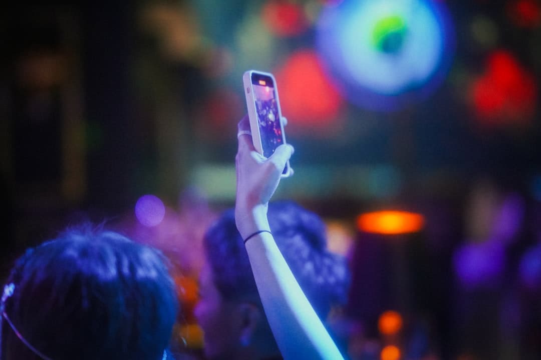 Invitados sacando fotos con el celular en una fiesta de noche