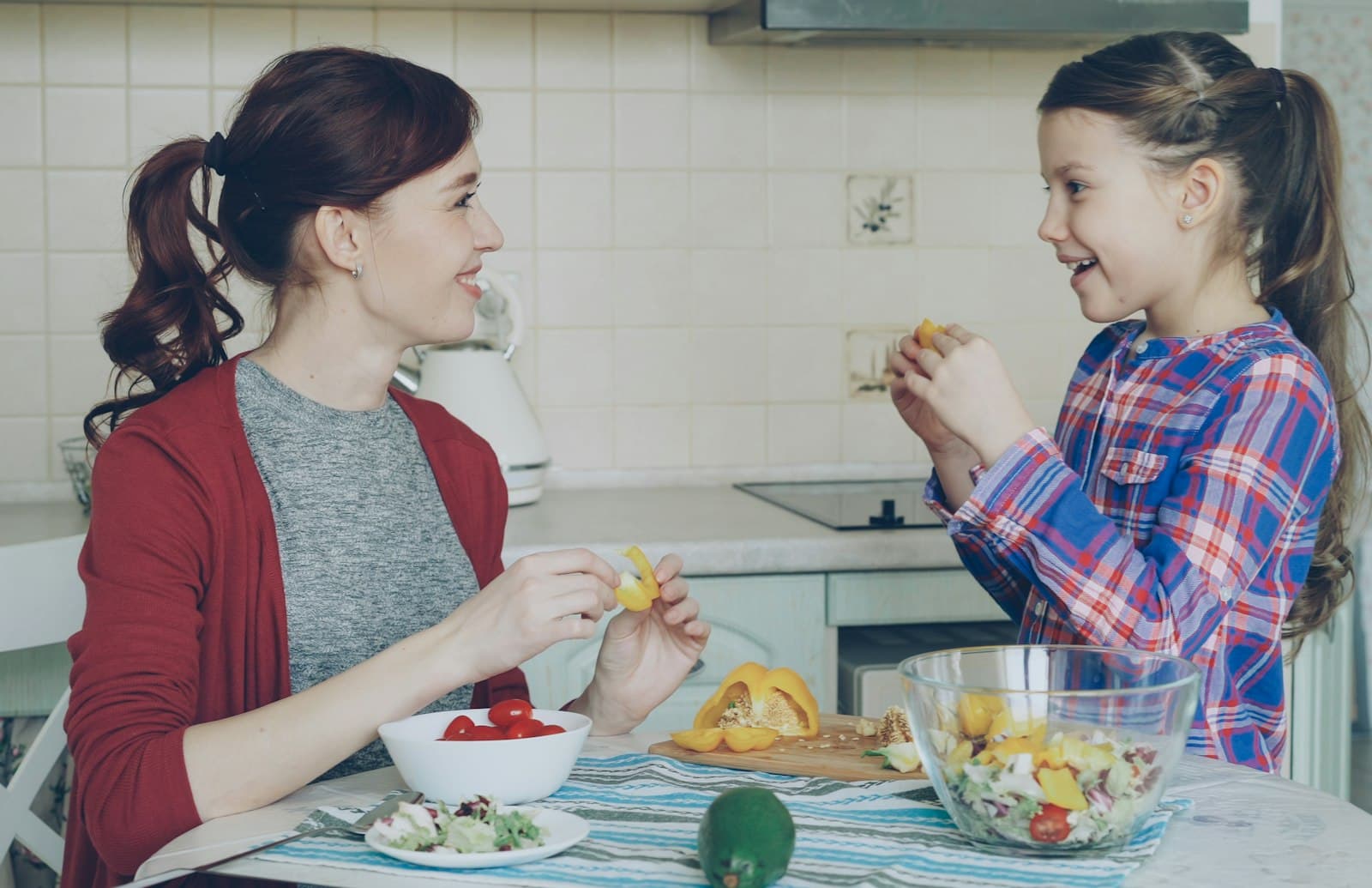 Madre e hija cocinando juntas en la cocina de su casa, riéndose