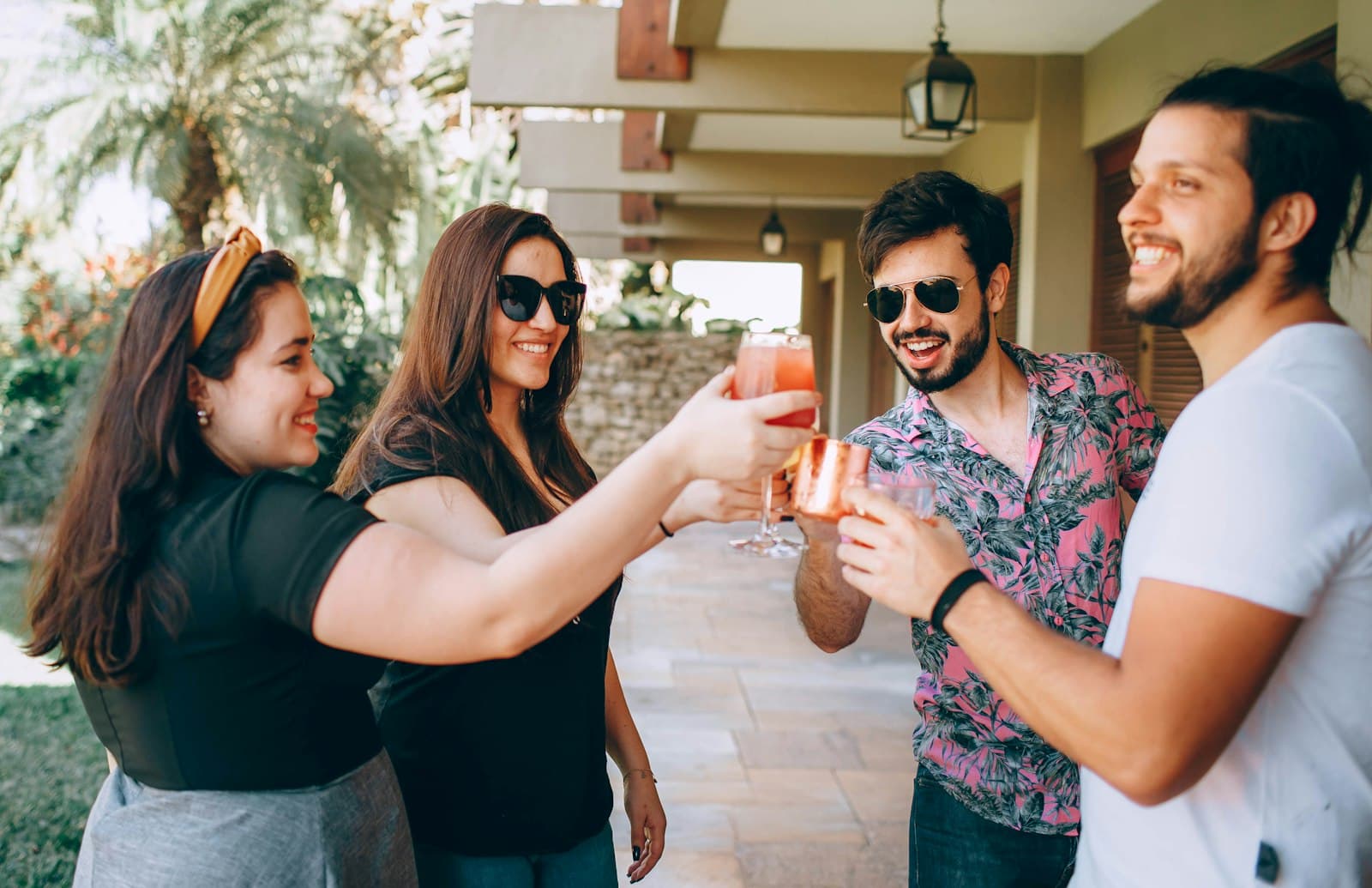 Grupo de amigos brindando con tragos en la galería de una casa