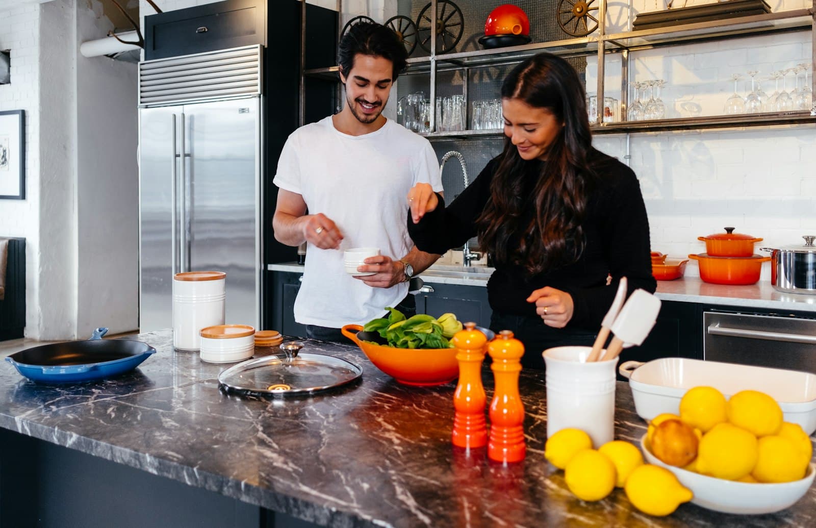 Pareja cocinando junta en la cocina de su casa, riéndose sobre la mesada