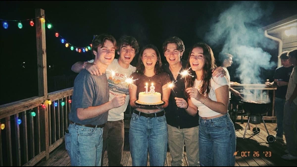 Amigos de 18 años con bengalas y una torta en una fiesta de noche