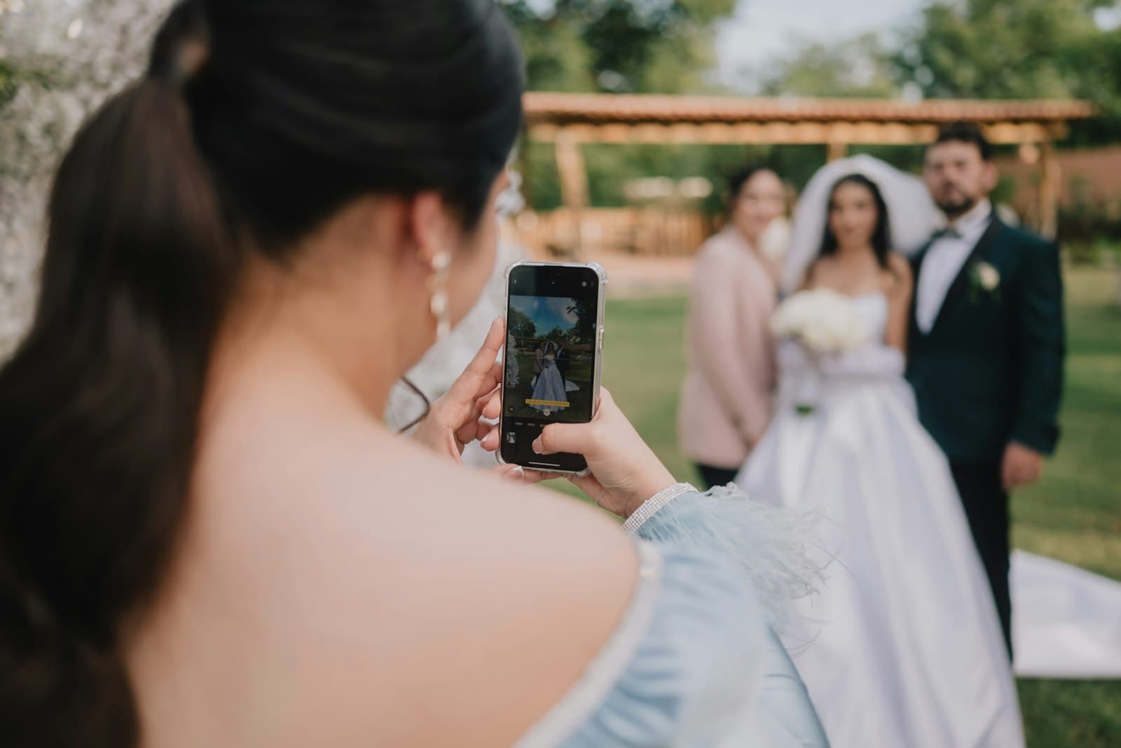 Invitada sacándole una foto con el celular a los novios