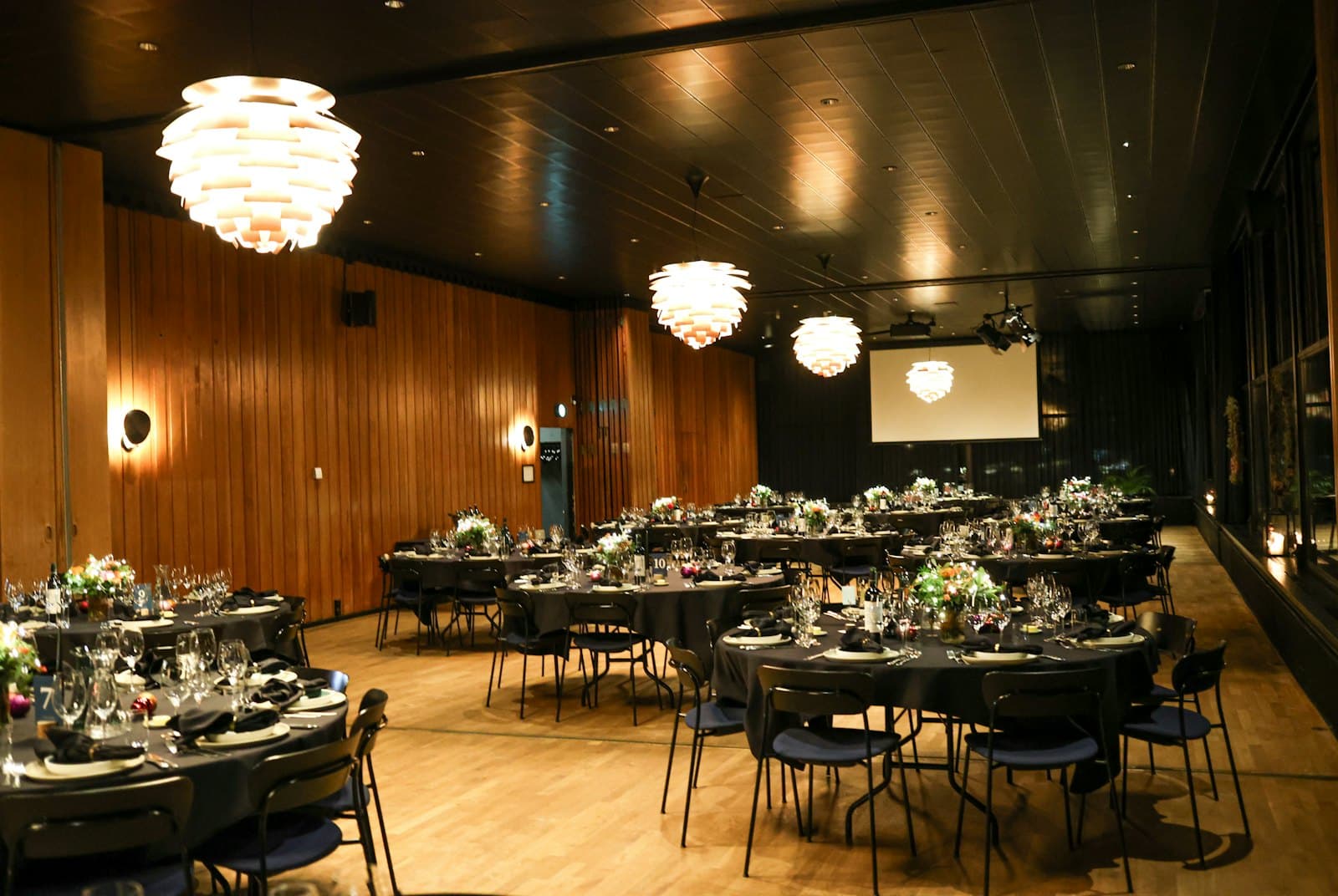 Salón de eventos armado con mesas redondas y centros de flores antes de la fiesta